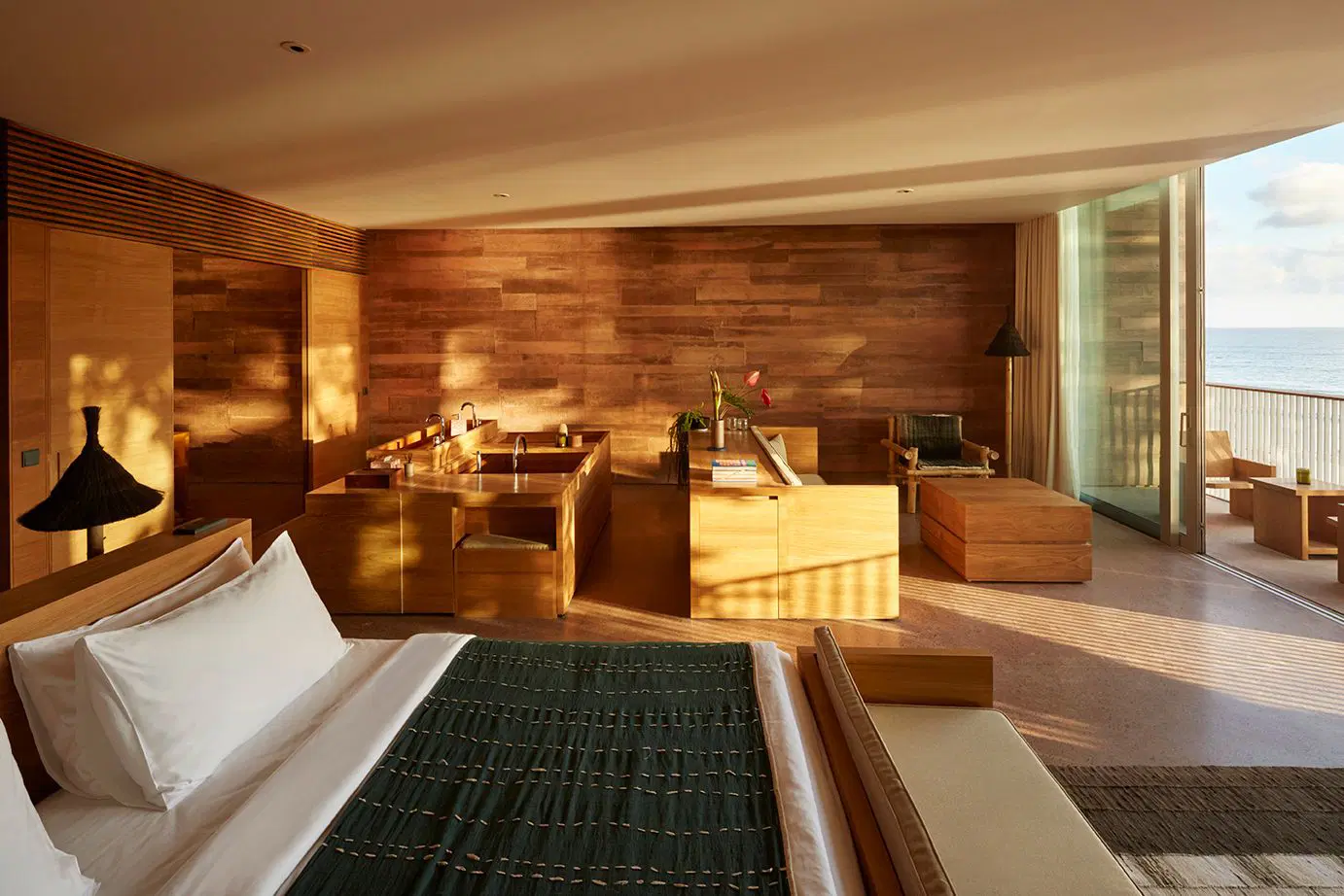 Room interior of Potato Head Bali's Oceanfront studio featuring a king-size bed and separate lounge area with sofa